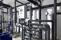 Industrial basement with heating pipes, pressure gauges, valves and heat exchangers.