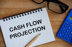 Cash flow projection text on notepad with calculator, pencil and glasses background. Business and cash flow concept