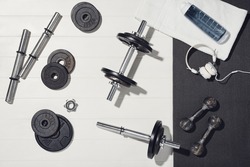 Fitness or bodybuilding concept on white wooden flooor background. Sport equipment for training at home. Photograph taken from above, top view with lots of copy space