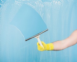 Cleaning concept - hand cleaning glass window pane with detergent and rubber aluminum wiper
