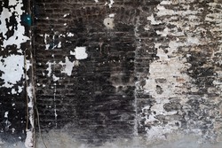 Old brick wall with black and white peeled off paint and soot and grime in a ruined factory in a lost place in Sauerland Germany. Shabby chick background with traces of former working place use.