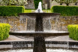Old fountain in the renovated historic gardens of Dalheim monastery “Kloster Dalheim“ in Lichtenau near Paderborn Germany. Sprinkeling well with perfect symmetry on a sunny springtime day.