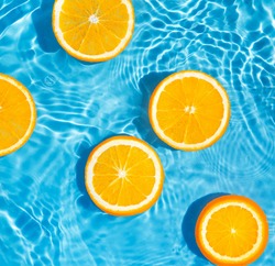 Creative summer composition made of sliced orange in transparent pool water. Refreshment concept. Healthy refreshing drink theme. Top view