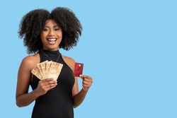 young black woman smiling holding brazilian money bills and a chip card, positively surprised, space for text, person, advertising concept, isolated on blue background