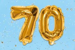 The number of the balloon made of golden foil, the number seventy on a blue background with sequins. Birthday greeting card with inscription 70. Anniversary concept. Celebration event.