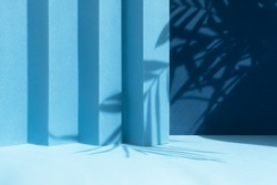 Abstract blue background with shadow of palm leaves for the presentation of a cosmetic product. A scene with a geometric backdrop. Podium for product promotion, beauty, natural eco cosmetic. Showcase.