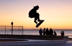silhouette of young skater jumping on ramp