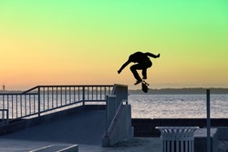 silhouette skateboarder jumping in a skatepark

