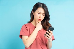 Beautiful Asian woman holding smartphone in hand with a thoughtful expression
