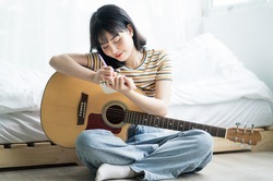 Young Asian girl is practicing guitar at home and composing music
