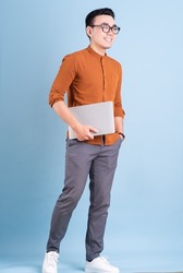 Young Asian businessman using laptop on blue background
