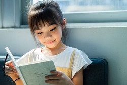 Asian child reading book at home