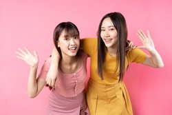 Two young Asian women on pink background