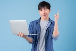 Young Asian man using laptop on blue background