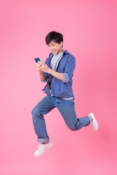 Young Asian man jumping on blue background