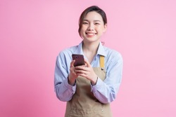 Young Asian waitress standing on pink background