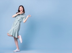 Full length image of young Asian woman wearing dress on blue background