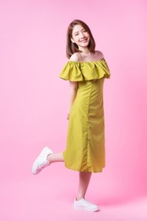 Image of young Asian woman wearing green dress on pink background