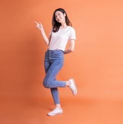 Full length image of young Asian woman posing on orange background