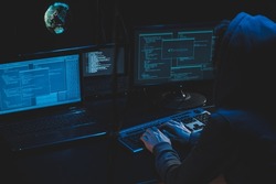 Cyber criminal hacking system at monitors, hacker attack web servers in dark room at computer with monitors sending virus using email vulneraility. Internet crime, hacking and malware concept. 