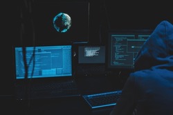 Cyber criminal hacking system at monitors, hacker attack web servers in dark room at computer with monitors sending virus using email vulneraility. Internet crime, hacking and malware concept.