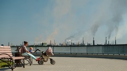Woman with baby sitting on a bench in a polluted city. environmental pollution and bad ecology in city concept 