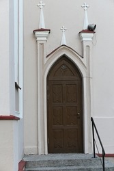 a fragment of the façade of a neo-Gothic church with a modest side entrance door