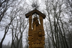 a wooden guardian sculpture against a background of bare park trees