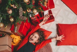 an attractive girl lies under a Christmas tree with gifts