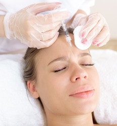 The beautician makes the patient injections and the forehead area during the procedure of mesotherapy and botulinum toxin