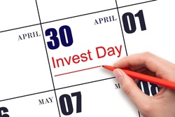 30th day of April.  Hand drawing red line and writing the text Invest Day on calendar date April 30.  Business and financial concept. Spring month, day of the year concept.