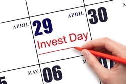 29th day of April.  Hand drawing red line and writing the text Invest Day on calendar date April 29.  Business and financial concept. Spring month, day of the year concept.