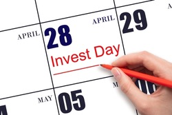 28th day of April.  Hand drawing red line and writing the text Invest Day on calendar date April 28.  Business and financial concept. Spring month, day of the year concept.