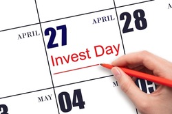 27th day of April.  Hand drawing red line and writing the text Invest Day on calendar date April 27.  Business and financial concept. Spring month, day of the year concept.