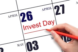 26th day of April.  Hand drawing red line and writing the text Invest Day on calendar date April 26.  Business and financial concept. Spring month, day of the year concept.