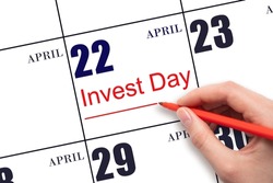 22nd day of April.  Hand drawing red line and writing the text Invest Day on calendar date April 22.  Business and financial concept. Spring month, day of the year concept.