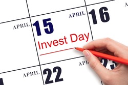 15th day of April.  Hand drawing red line and writing the text Invest Day on calendar date April 15.  Business and financial concept. Spring month, day of the year concept.
