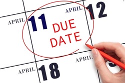 11th day of April. Hand writing text DUE DATE on calendar date April 11 and circling it. Payment due date. Business concept. Spring month, day of the year concept.