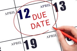 12th day of April. Hand writing text DUE DATE on calendar date April 12 and circling it. Payment due date. Business concept. Spring month, day of the year concept.