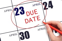 23rd day of April. Hand writing text DUE DATE on calendar date April 23 and circling it. Payment due date. Business concept. Spring month, day of the year concept.