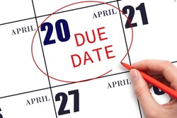 20th day of April. Hand writing text DUE DATE on calendar date April 20 and circling it. Payment due date. Business concept. Spring month, day of the year concept.