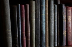 row of old books in the dark, without title