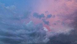Clouds in the blue sky at sunset or dawn backlit by the sun. Place for text and design. Heaven and clouds with copy space. Looking up in the sky. Background picture. View into infinity