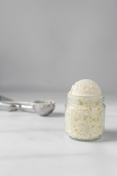 Scoop of american buttercream in a glass jar, scoops of buttercream with air pockets, textured buttercream in a glass jar, scoops of ice cream in glass cup
