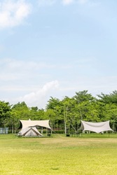 Camping tents on the grassland of the park under the blue sky and white clouds