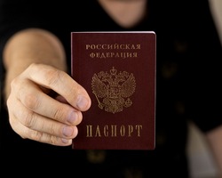 Title: Passport of the Russian Federation. A human hand with a Russian passport in close-up. The concept of obtaining citizenship of the Russian Federation. Close-up, selective focus, blur.