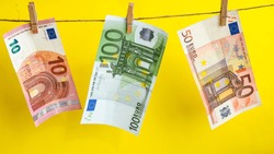 euros on a rope, euro with a clothespin on a rope isolated on a yellow background, Concept - money laundering. euro are dried on the ropes. euros after washing. Money earned honestly. Legalization of