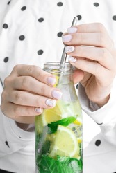 Female hand holding Mojito refreshing cocktail with eco metal drinking straw, alcohol drink. Lemonade with lemon and mint leaves. Summer refreshing detox drinks. Clean eating, healthy lifestyle 