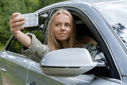 Blonde woman stoped car on road to take a selfie photo. Young tourist explore local travel making candid real moments. True emotions expressions of getting away and refresh on open air