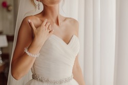 Exciting moment of waiting for groom, wedding day, unrecognizable bride looking out window. Concept of bride's gathering for celebration. High quality photo